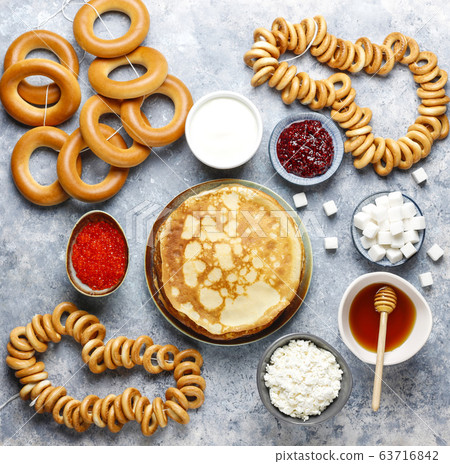Shrovetide Maslenitsa festival meal. Russian pancake blini with raspberry jam, honey, fresh cream and red caviar,sugar cubes,cottage cheese,bubliks on light background 63716842