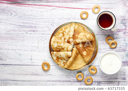 Shrovetide Maslenitsa festival meal. Russian pancake blini with raspberry jam, honey, fresh cream and red caviar,sugar cubes,cottage cheese,bubliks on light background 63717335