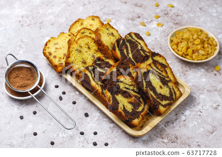 Traditional raisin marble cake slices with raisins and cocoa powder on light background,top view 63717728