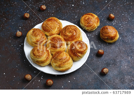 Azerbaijan national pastry qogal on white plate on dark background ,top view,spring new year celebration Novruz holiday. Azerbaijan national pastry qogal on white plate on dark background ,top view,spring new year celebration Novruz holiday. 63717989
