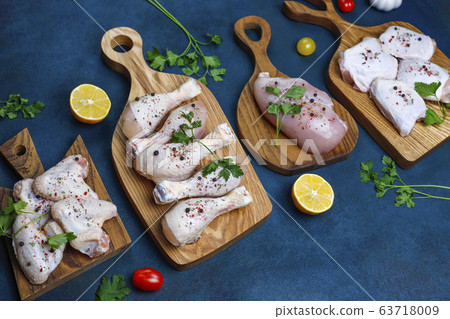 Raw chicken meat fillet, thigh, wings and legs with herbs ,spices,lemon and garlic on dark blue background. Top view Raw chicken meat fillet, thigh, wings and legs with herbs ,spices,lemon and garlic on dark blue background. Top view 63718009