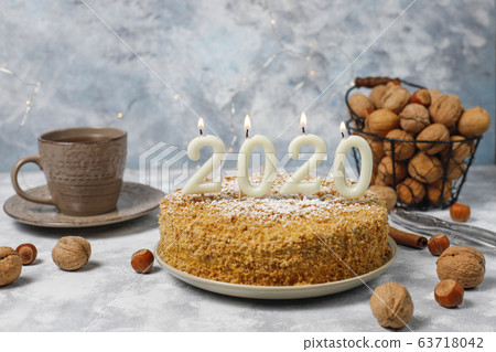 Carrot cake with 2020 candles and a cup of tea on grey concrete background Carrot cake with 2020 candles and a cup of tea on grey concrete background 63718042