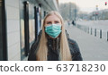 Young blonde woman wearing a protective medical mask on the street 63718230