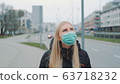 Concerned woman in medical coronavirus mask walking on the street 63718232