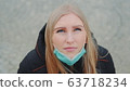 Crane shot of blonde woman looking into the sky and putting on medical mask 63718234