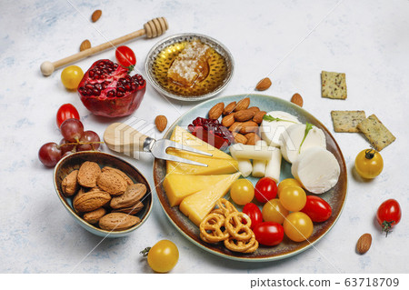 Various cheese and cheese plate on light table with different nuts and fruits 63718709