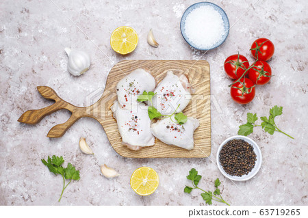 Raw chicken thighs with spices parsley on wooden cutting board,top view 63719265