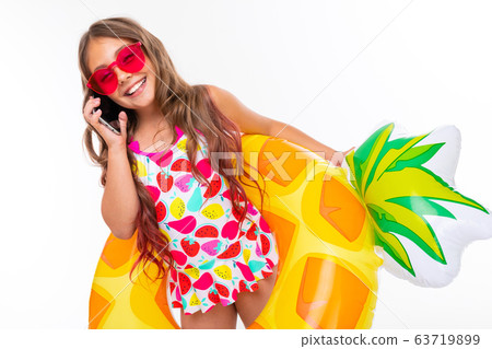 teenager girl in swimming clothes among swimming circles and mattresses on vacation on an isolated 63719899