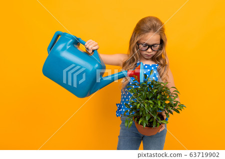 girl watering a potted houseplant on a yellow background with copy space girl watering a potted houseplant on a yellow background with copy space 63719902