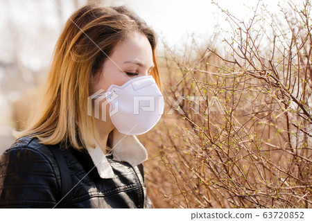 Woman trying to smell open leaves in a protective Woman trying to smell open leaves in a protective 63720852
