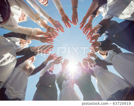 Students graduates make the shape of a circle from the palms of their hands. 63720919