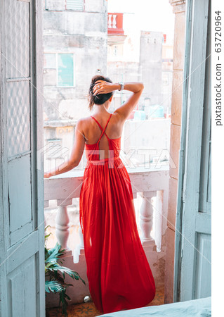 Young attractive woman in red dress on old balcony in apartment in Havana Young attractive woman in red dress on old balcony in apartment in Havana 63720964
