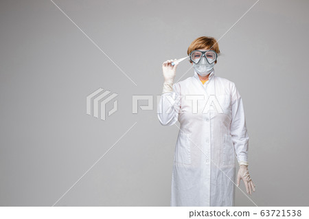 Physician in mask is holding thermometer in studio Physician in mask is holding thermometer in studio 63721538