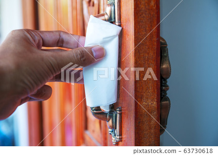 Using hand open the door with paper wipe on knob prevent covid19 virus. Using hand open the door with paper wipe on knob prevent covid19 virus. 63730618