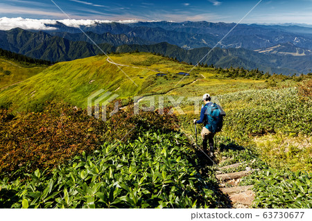 Hikers going along the mountain ridge line 63730677
