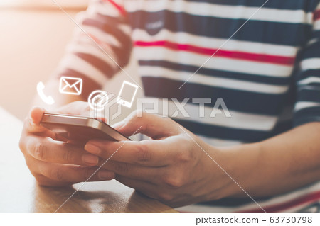 Close-up image of male hands using smartphone with icon telephone email mobile phone and address 63730798