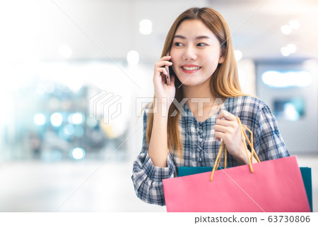 Smiling young Asian woman with shopping colour Smiling young Asian woman with shopping colour 63730806