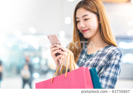 Smiling young Asian woman with shopping colour Smiling young Asian woman with shopping colour 63730807