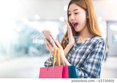 Smiling young Asian woman with shopping colour Smiling young Asian woman with shopping colour 63730808