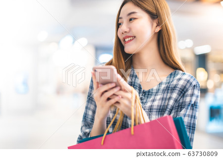 Smiling young Asian woman with shopping colour Smiling young Asian woman with shopping colour 63730809