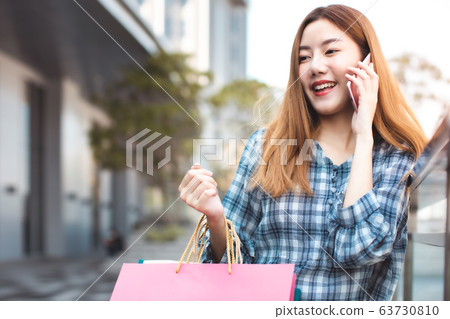 Smiling young Asian woman with shopping colour Smiling young Asian woman with shopping colour 63730810