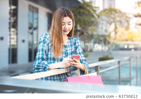 Smiling young Asian woman with shopping colour Smiling young Asian woman with shopping colour 63730812