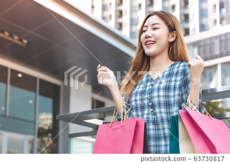 Smiling young Asian woman with shopping colour Smiling young Asian woman with shopping colour 63730817
