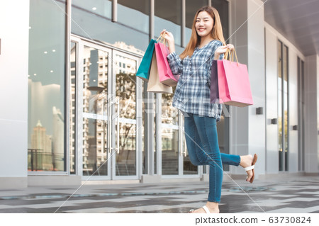 Smiling young Asian woman with shopping colour Smiling young Asian woman with shopping colour 63730824