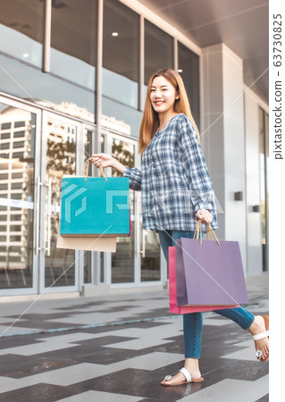 Smiling young Asian woman with shopping colour Smiling young Asian woman with shopping colour 63730825