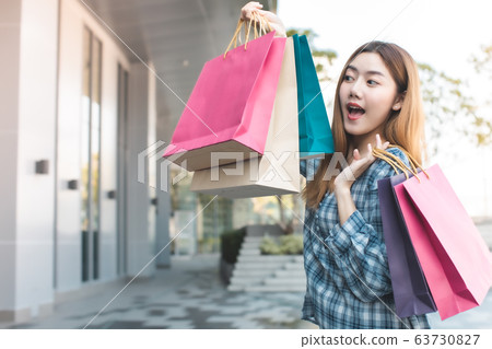 Smiling young Asian woman with shopping colour Smiling young Asian woman with shopping colour 63730827