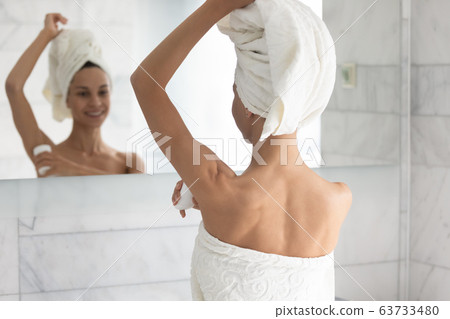 After shower woman apply at armpit area antiperspirant rear view After shower woman apply at armpit area antiperspirant rear view 63733480