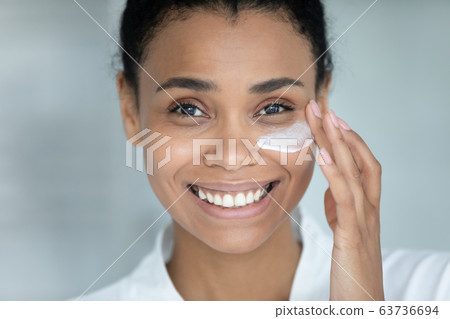 Close up face african beautiful woman apply cream on skin 63736694