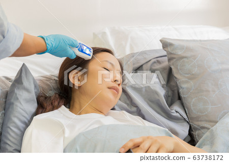 Hand with digital thermometer to measures woman while sleeping from coronavirus. 63738172
