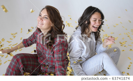 Beautiful happy women smiles through gold glitter confetti on a white background Beautiful happy women smiles through gold glitter confetti on a white background 63741874