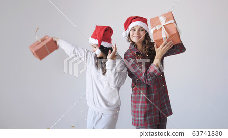 Happy women in Christmas cap shaking gift boxes. Concept of holidays Happy women in Christmas cap shaking gift boxes. Concept of holidays 63741880