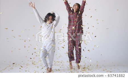 Beautiful happy women dancing through gold glitter confetti on a white background 63741882
