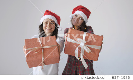 Young happy woman in Christmas cap gives a gift box on a white background. Holidays packaging, wrapping. 63741926
