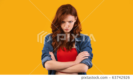 Sulky Teen Girl Crossing Hands Over Yellow Studio Background 63742926