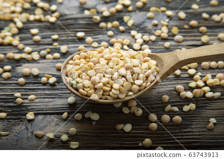 Dry yellow peas in a spoon on a brown wooden Dry yellow peas in a spoon on a brown wooden 63743913