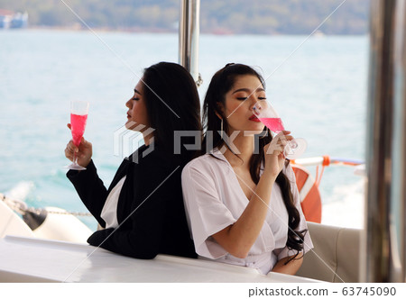 Beautiful two asia woman traveling for relaxation and drinking wine on speed boat at Thailand. Beautiful two asia woman traveling for relaxation and drinking wine on speed boat at Thailand. 63745090