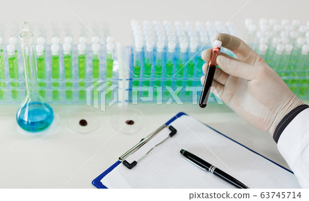 Close up photo of a doctor's hands with a test tube with a blood sample. Close up photo of a doctor's hands with a test tube with a blood sample. 63745714