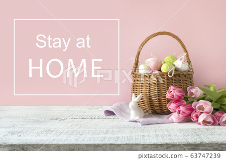 Wicker basket with easter eggs and pink tulips. 63747239
