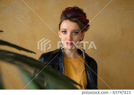 Glamorous lady in punk rock style party clothes with dark pink hair in casual dress, black leather jacket, and long earrings on yellow background Glamorous lady in punk rock style party clothes with dark pink hair in casual dress, black leather jacket, and long earrings on yellow background 63747815