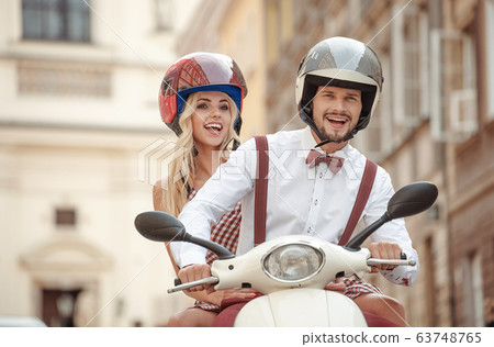 happy young couple having fun riding the scooter 63748765