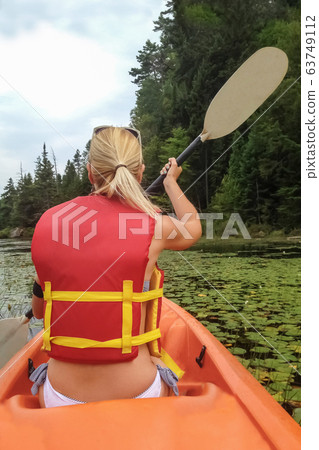 Girl kayaking on the lake with water lilies Girl kayaking on the lake with water lilies 63749112