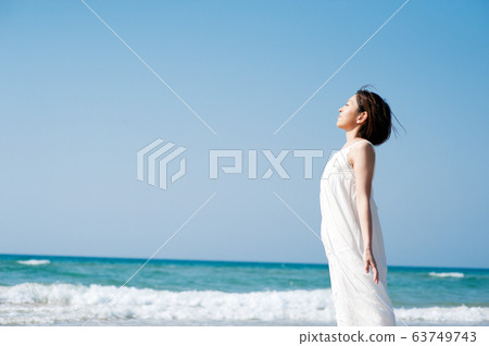 A woman bathed in light on a sandy beach 63749743