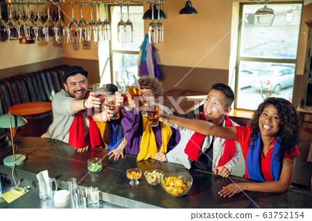 Sport fans cheering at bar, pub and drinking beer while championship, competition is going Sport fans cheering at bar, pub and drinking beer while championship, competition is going 63752154