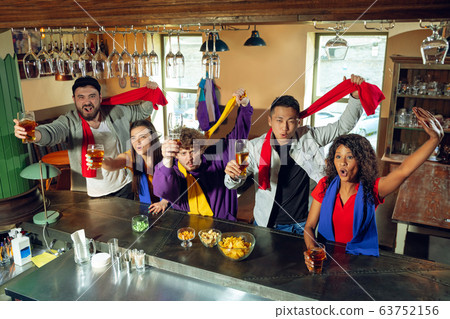 Sport fans cheering at bar, pub and drinking beer while championship, competition is going Sport fans cheering at bar, pub and drinking beer while championship, competition is going 63752156
