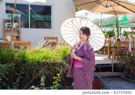 The girl is wearing a pink traditional yukata, which is the national dress of Japan and Hold an umbrella The girl is wearing a pink traditional yukata, which is the national dress of Japan and Hold an umbrella 63755992