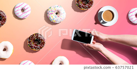 Person using a smartphone with donuts 63757021